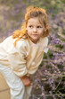 © dtatiana - Little girl walking in the park in autumn and touching flowers in the garden. A cute girl in white clothes is standing in a flower alley.