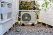 © Bartek - Outdoor Air Conditioning Unit Between White Wooden Structures in Pebbled Alleyway