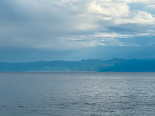 Dramatic lakeside scene at Lake Ohrid, North Macedonia. Stormy sky casting shadows over hills and mountains. Brewing storm with dark clouds accumulating. Power and beauty of nature. Boat tour