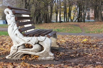 Ornate Bench in Autumn Park with Fallen Leaves and Bare Trees