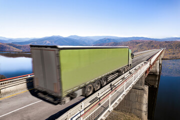 Wall Mural - Green truck moving by a bridge over the river