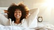 © PBMasterDesign - Happy woman relaxing in bed with a smile in a bright, sunny room.