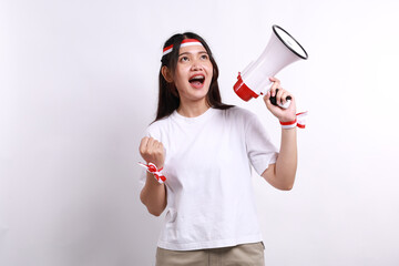 excited asian woman wearing red white flag ribbon, shouting using a megaphone while clenching hand, 