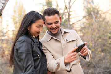 young couple using smartphone together in the city street