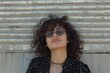 © Isuru - Content adult overweight female in eyewear curly hair against ribbed wall in daytime