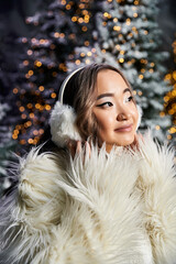 Wall Mural - A young woman in cozy winter wear enjoys the Christmas spirit in a festive backdrop.