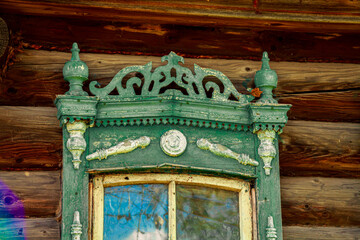 Wall Mural - Old houses. Carved window frames. View of a fragment of a house wall with carved decorations around the window and doors. Traditional Russian old houses. Close-up. Front view. Landscape.