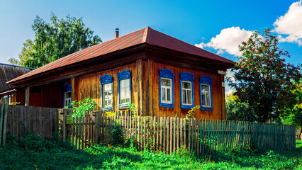 Wall Mural - Old houses. Carved window frames. View of a fragment of a house wall with carved decorations around the window and doors. Traditional Russian old houses. Close-up. Front view. Landscape.