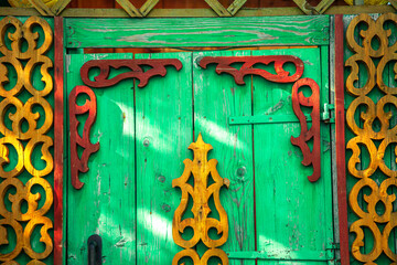 Wall Mural - Old houses. Carved window frames. View of a fragment of a house wall with carved decorations around the window and doors. Traditional Russian old houses. Close-up. Front view. Landscape.