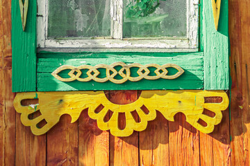 Wall Mural - Old houses. Carved window frames. View of a fragment of a house wall with carved decorations around the window and doors. Traditional Russian old houses. Close-up. Front view. Landscape.