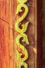 Wall Mural - Old houses. Carved window frames. View of a fragment of a house wall with carved decorations around the window and doors. Traditional Russian old houses. Close-up. Front view. Landscape.