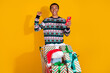 © deagreez - Photo of young man excited push shopping cart gifts winner device dressed ornament clothes christmas theme party on yellow color background