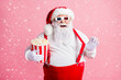 © deagreez - Portrait of his he nice attractive cheerful cheery funny bearded fat Santa watching film eating corn having fun amusement pulling suspender fooling isolated pink pastel color background