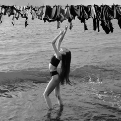 one alone Woman with raised arms on vacation walking at the beach. lady female slim 1 girl with long brunette hair in bikini is walking along the shore of the sea or ocean. hands up. holiday maker.