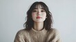 © Jittapon - Portrait shot of a cheerful and radiant young Japanese woman dressed in a soft cozy and oversized sweater against a plain white background with ample copy space above the subject
