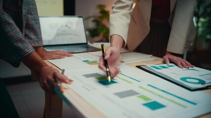 Fototapete - Two businesswomen are collaborating on a project, standing by a table and reviewing financial reports. They are pointing at charts and graphs, discussing data and insights