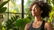 © OHMAl2T - Young woman meditating in a lush indoor garden