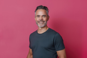 Confident Middle-Aged Man in Grey T-Shirt Against Vibrant Pink Background for Lifestyle Concept