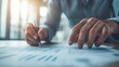 © Khuefa - Close-up of hands writing on documents at a desk, symbolizing business planning and analysis.