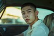 © pham - 車の中で考え込む若い男性のポートレート、背景には夕暮れの街並みが広がる