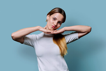 Wall Mural - Portrait of beautiful young girl with long red hair looking at camera on blue background