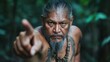 © JoxyAimages - A focused man with tattoos intensely gestures toward something in the dense jungle, capturing a sense of urgency, strength, and connection to the elements.