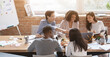 © Prostock-studio - Friendly multiethnic business team sitting around table, having meeting in office