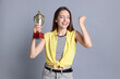 © New Africa - Happy winner with gold trophy cup on gray background