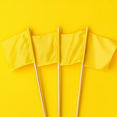 Three yellow flags on wooden sticks against a bright yellow background.