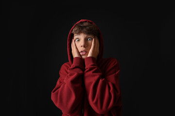 Portrait of scared teenage boy on black background