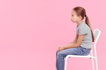 Wall Mural - Girl with incorrect posture sitting on chair against pink background, space for text