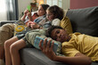 © pressmaster - Group of teenagers lounging on sofa, immersed in using their smartphones. Cozy living room setting with relaxed atmosphere and modern furniture
