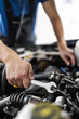© zphoto83 - A mechanic works on a car engine using a wrench in a well-lit garage during the afternoon