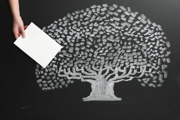 Wall Mural - Woman holding blank paper sheet over chalkboard with tree drawing, closeup