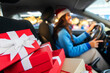 © Home-stock - Selective focus on pale of wrapped Xmas gift boxes in car while woman in Santa hat driving from shopping mall