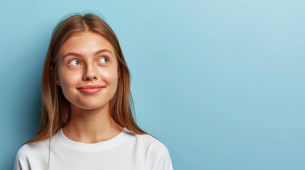 Wall Mural - A cheerful lady in a tshirt touches her shoulder, gazing off into an empty space against a vibrant teal backdrop.