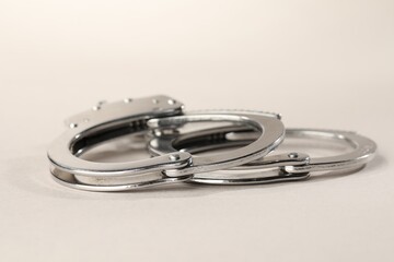 Metal chain handcuffs on light grey background, closeup