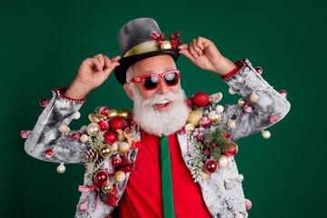 Wall Mural - Photo of cool pensioner santa claus male touch hat dressed balls baubles on jacket sunglass isolated on green color background