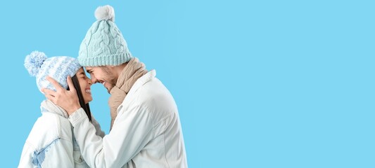 Wall Mural - Loving couple in winter clothes on blue background with space for text