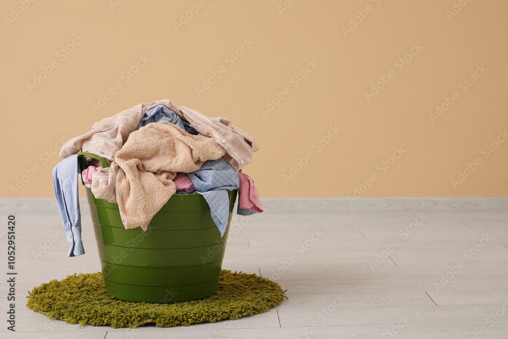 Green basket with laundry on floor near beige wall