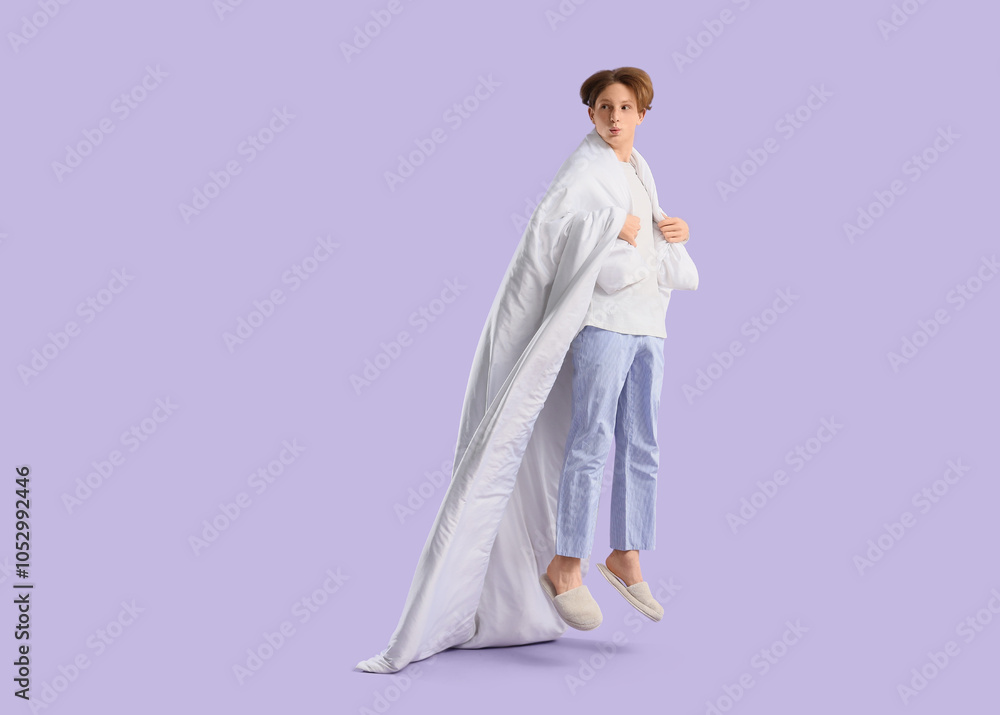 Jumping young man in pajamas with blanket on lilac background