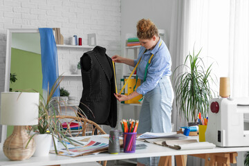 Wall Mural - Female fashion designer measuring jacket on mannequin in studio