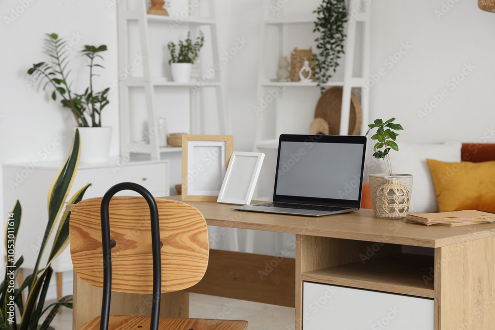 Blank laptop with frames on programmer's desk in living room