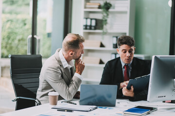 Two businessmen working together Analyze financial reports with charts and graphs while using the calculator to calculate budget, income, taxes, business growth. Startup business idea.