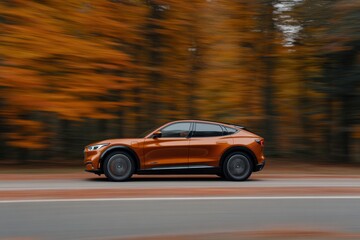 Modern orange electric suv crossover car driving on the road in autumn forest