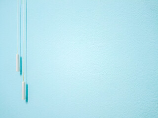 Minimalist style background from a blue wall decorated with a rope to turn on the fan, plus the light and shadows that shine on the wall, it looks beautiful and unique.