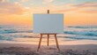 © Andrew - A large blank canvas mockup on an easel positioned on a quiet beach at sunset