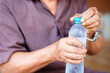 © Oporty786 - person opening plastic water bottle, focusing on hands and bottle. image captures action in casual setting, highlighting texture of bottle and persons hands