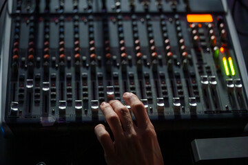 Close-Up of a Hand Operating an Audio Mixing Console in a Dimly Lit Studio, Professional Sound Engineering Setup