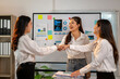 © Wasana - Three women are shaking hands in a business setting